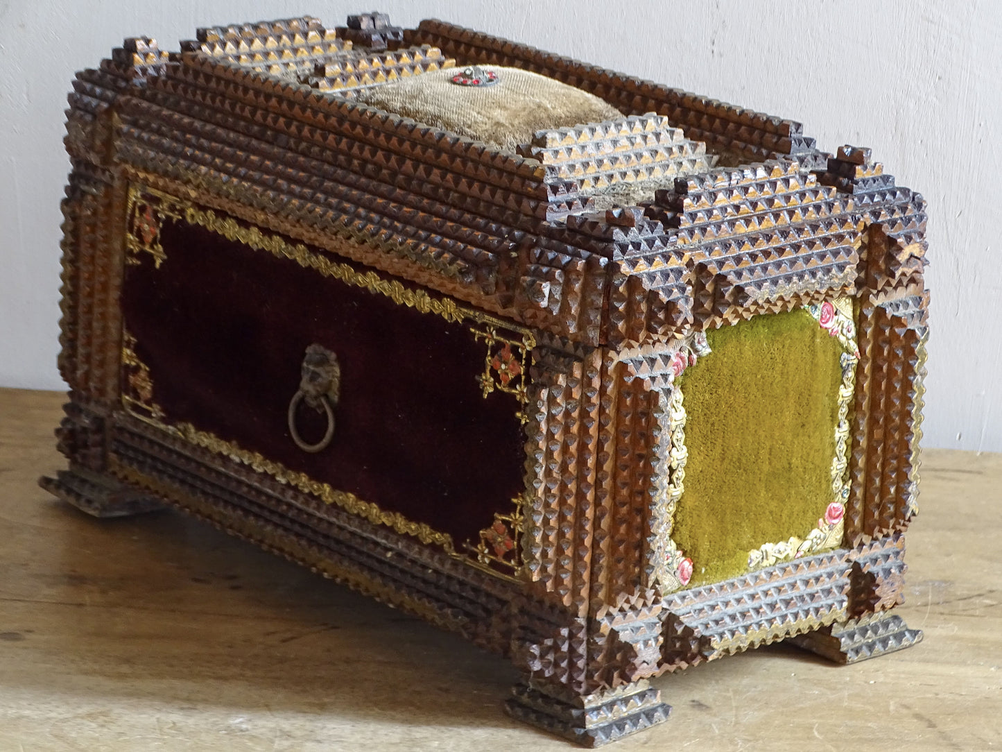 Side view of antique tramp art jewellery box with burgundy velvet front, olive side panel and decorative lion-head ring.