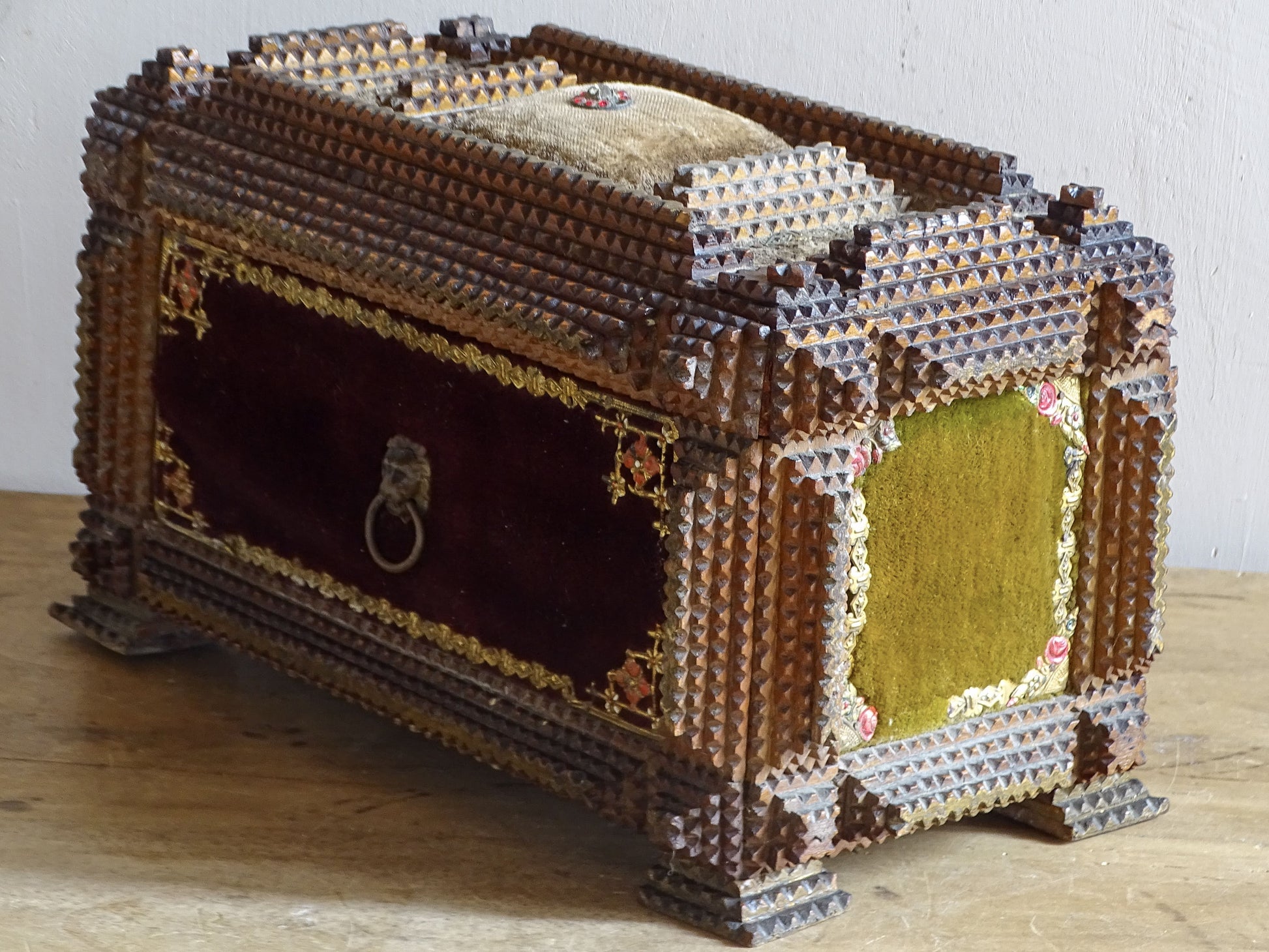 Side view of antique tramp art jewellery box with burgundy velvet front, olive side panel and decorative lion-head ring.