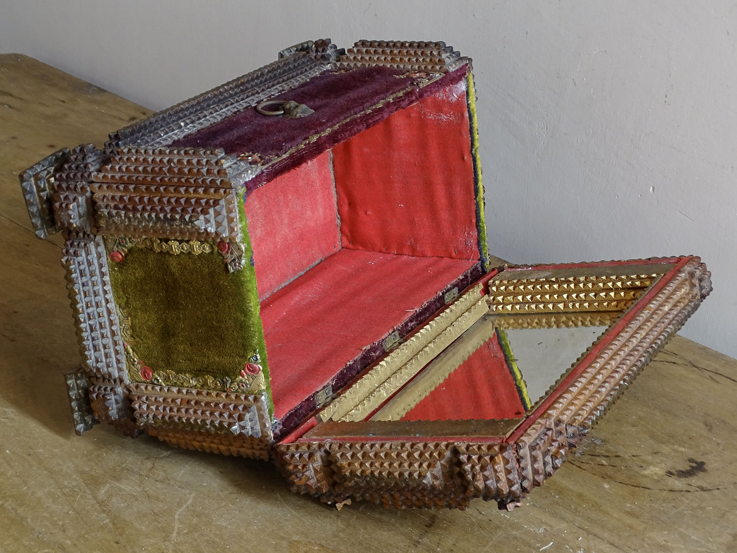 Open antique tramp art box viewed from above, showing the mirrored lid, red-lined compartment and geometric chip-carved decoration.