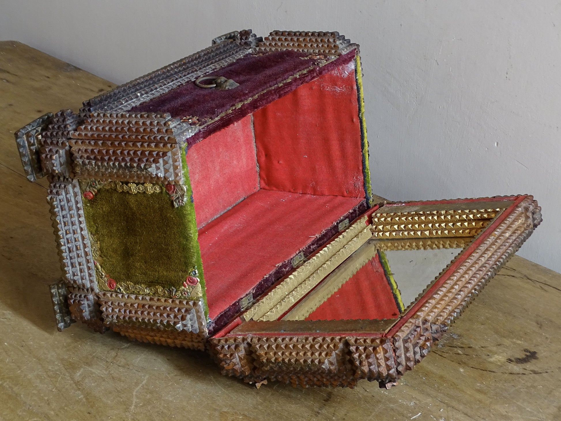Open antique tramp art box viewed from above, showing the mirrored lid, red-lined compartment and geometric chip-carved decoration.