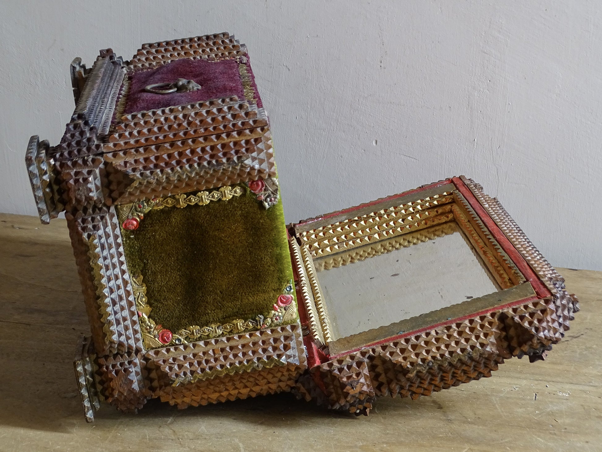 Side view of antique tramp art sewing box opened to reveal the red fabric-lined compartment and mirror inside the lid.