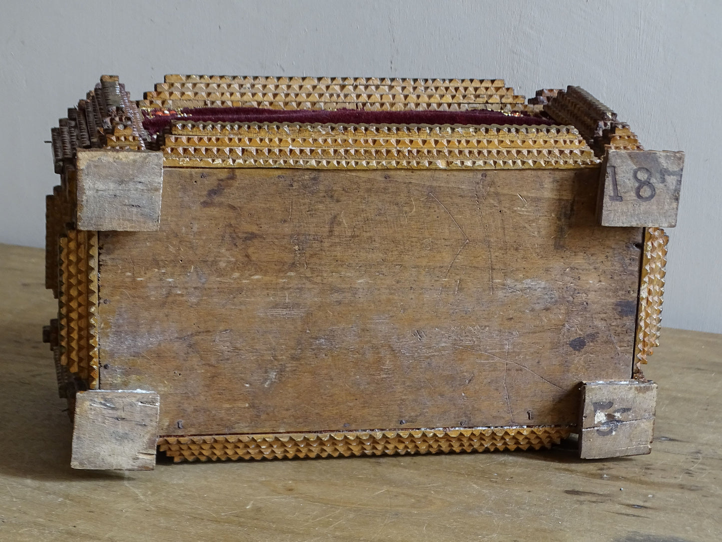 Underside of antique tramp art box showing the original wooden base, raised block feet and old numbered markings.