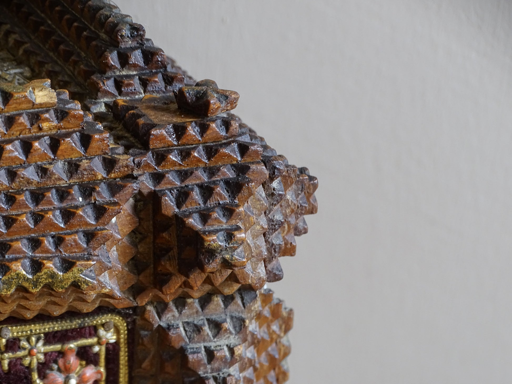 Detailed view of stepped geometric carving and projecting corner decoration on an antique tramp art box.