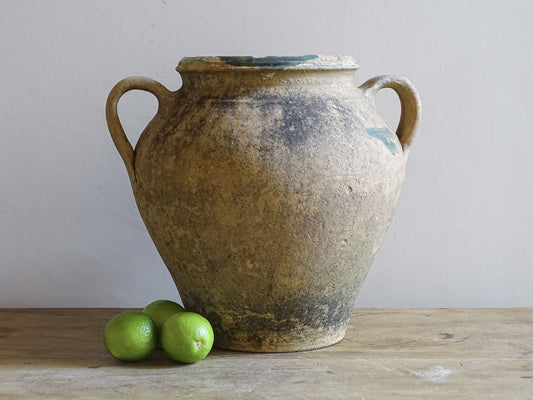 Weathered 19th-century French terracotta pot with worn green glaze displayed with a lime for scale