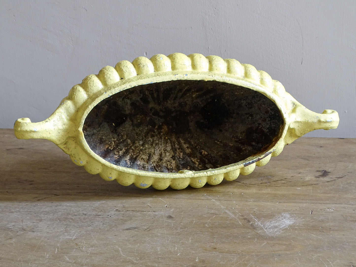 Antique French jardinière planter in yellow painted cast iron with ribbed detailing and scrollwork.