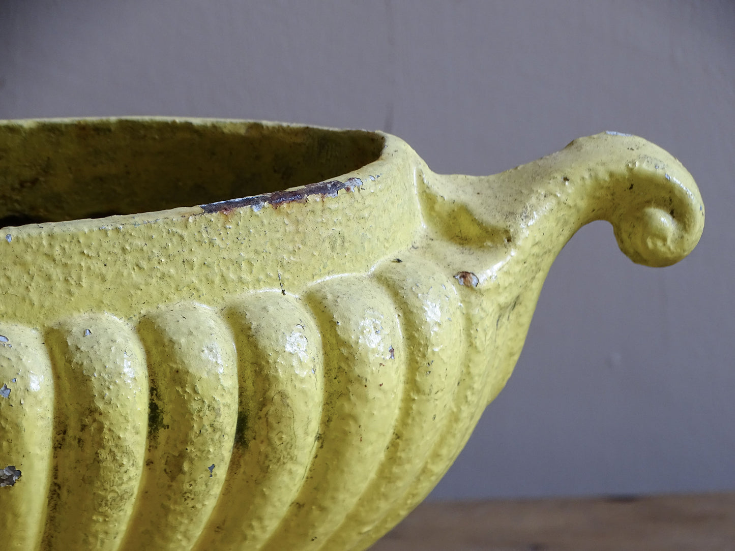 Decorative French cast iron planter with timeworn yellow finish and naturally aged iron.