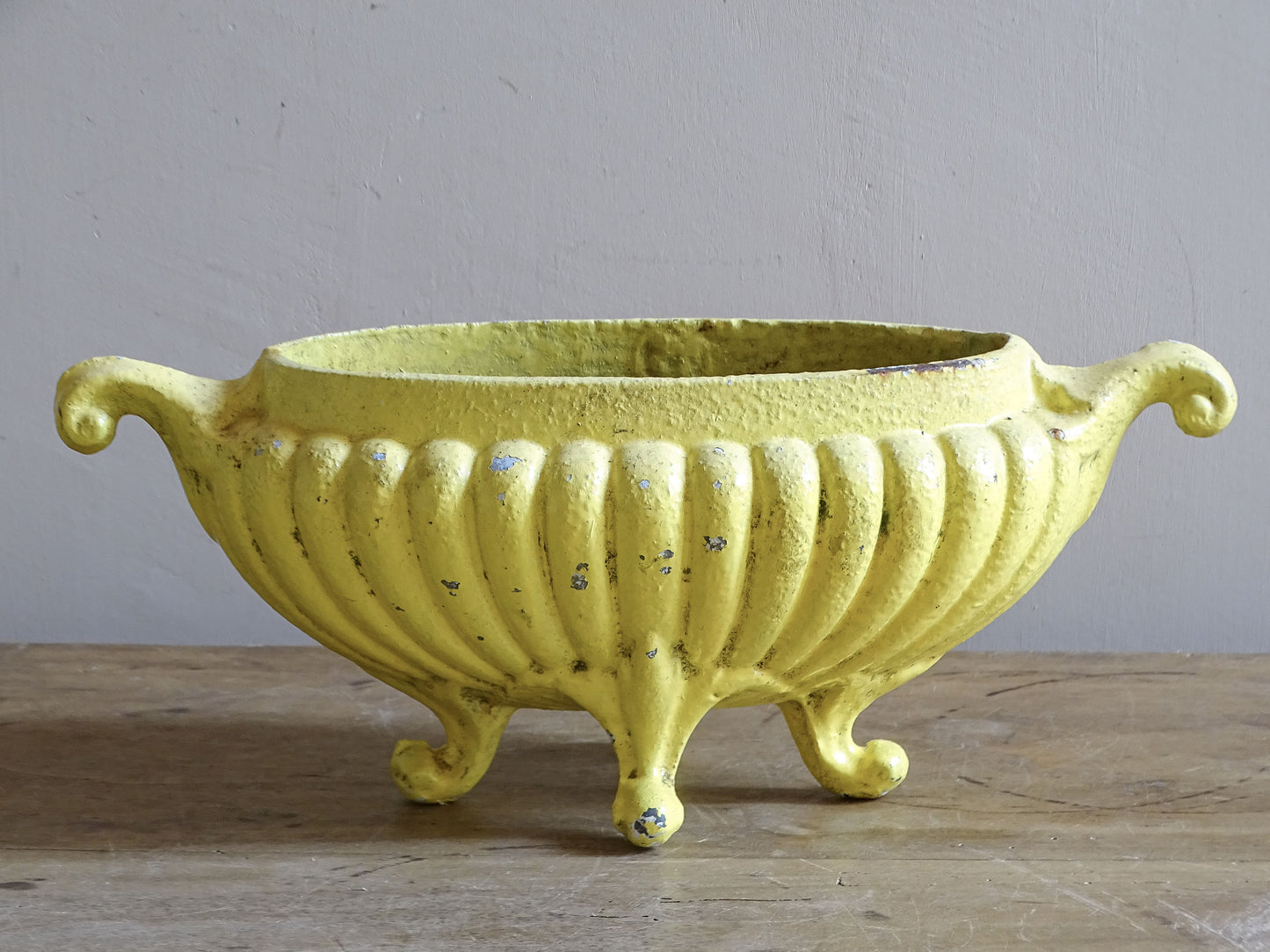 Antique yellow cast iron planter from France with an elongated ribbed body and side handles.