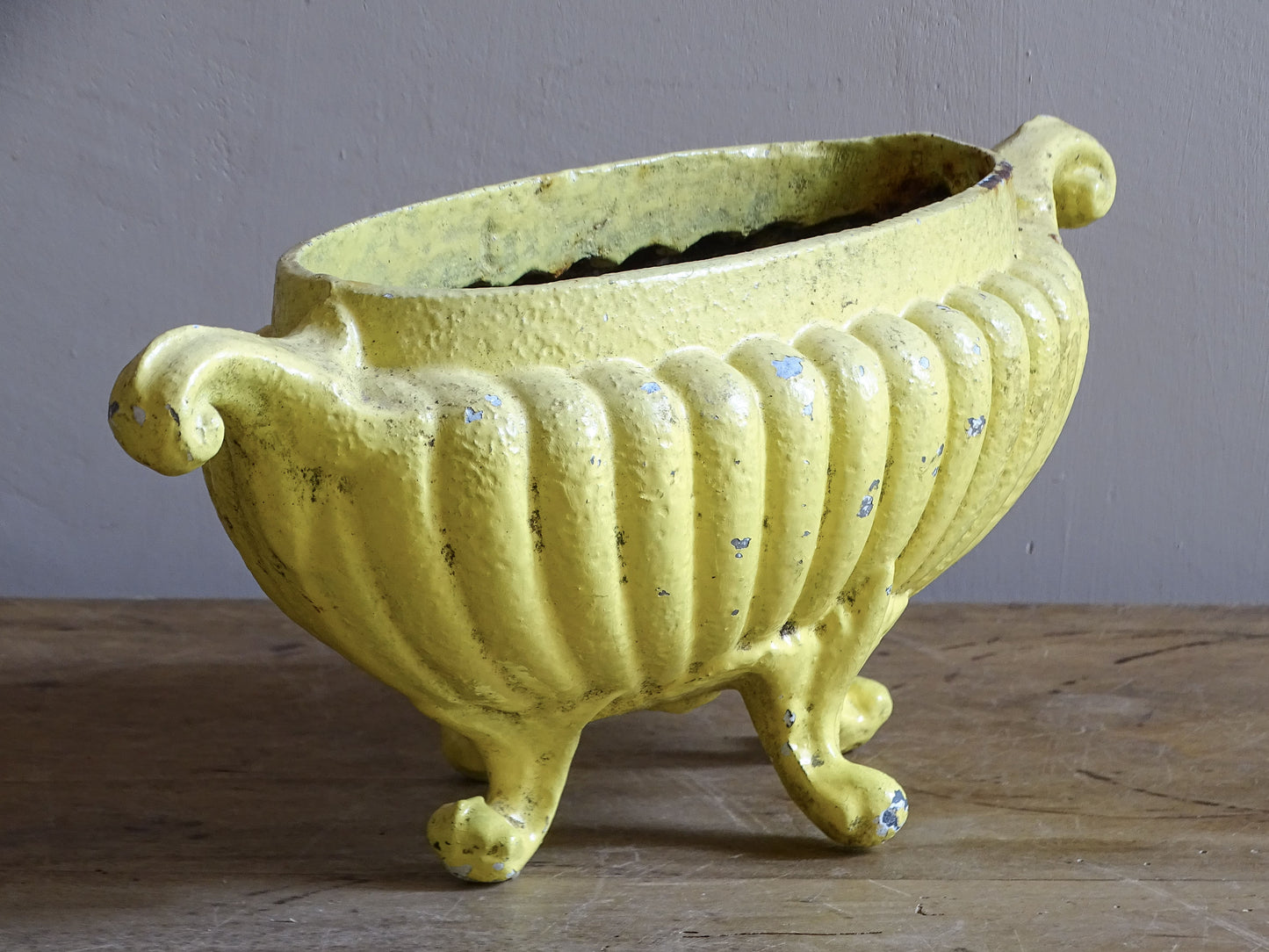 Circa 1900 French cast iron jardinière with decorative yellow paint and scrolling feet.