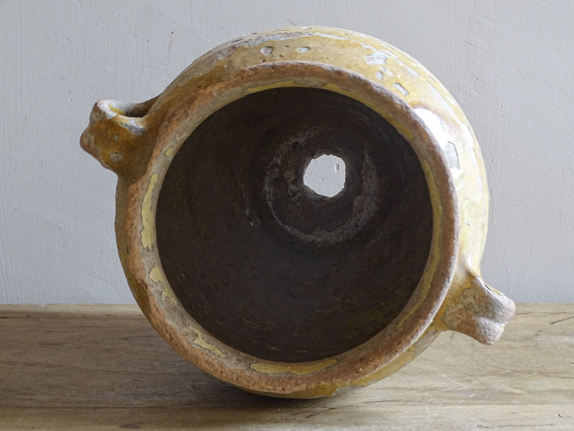 Interior view of an antique French confit pot showing the later drainage hole through the base.
