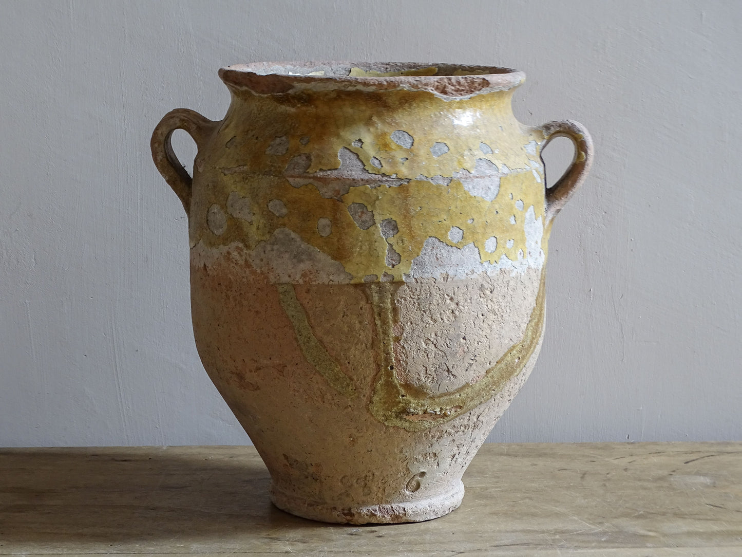 Antique French confit pot with twin handles, worn yellow glaze and decorative glaze runs over the unglazed earthenware body.