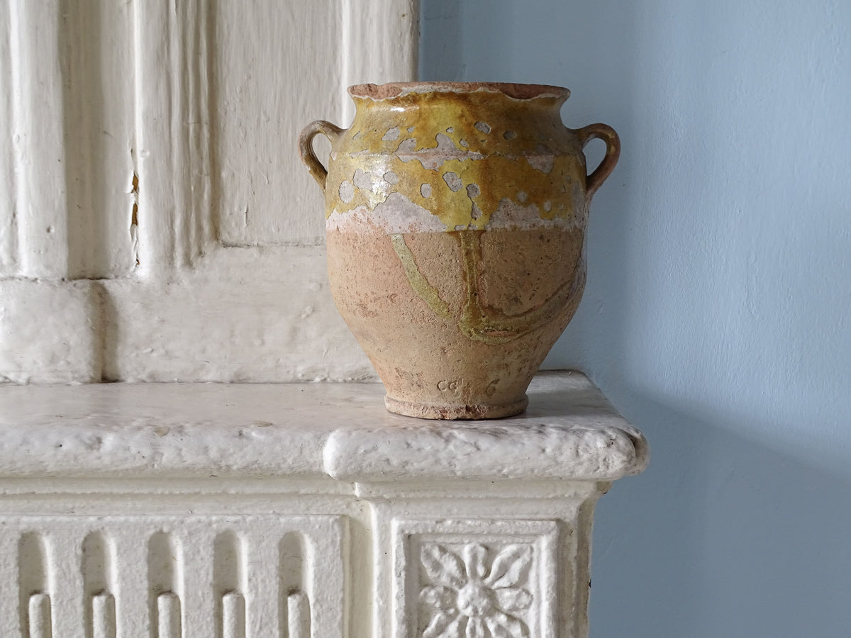 French antique confit pot with yellow glaze pictured on a country house fireplace