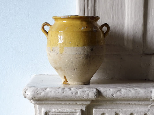 Antique French confit pot with yellow glaze on an old country house fireplace mantel 
