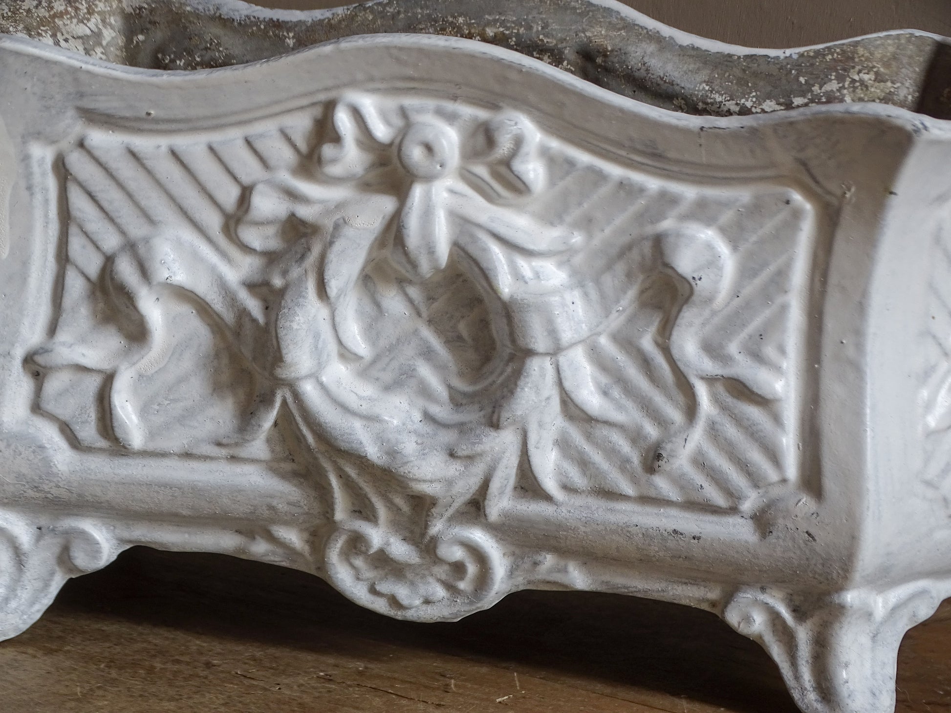 Antique French cast iron jardinière planter with ornate floral relief decoration, scrolling handles and an aged white painted finish.
