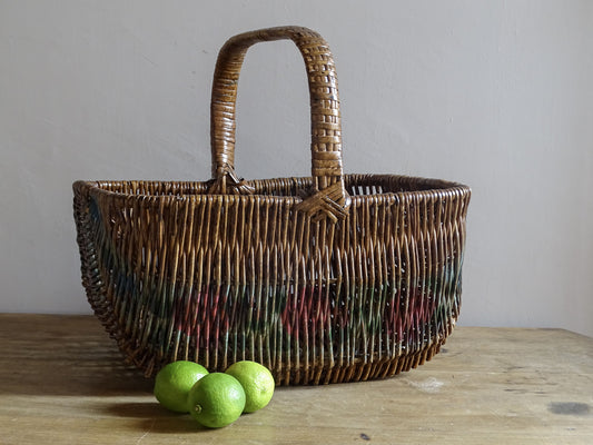 Vintage French painted wicker market basket displayed with fresh green limes.