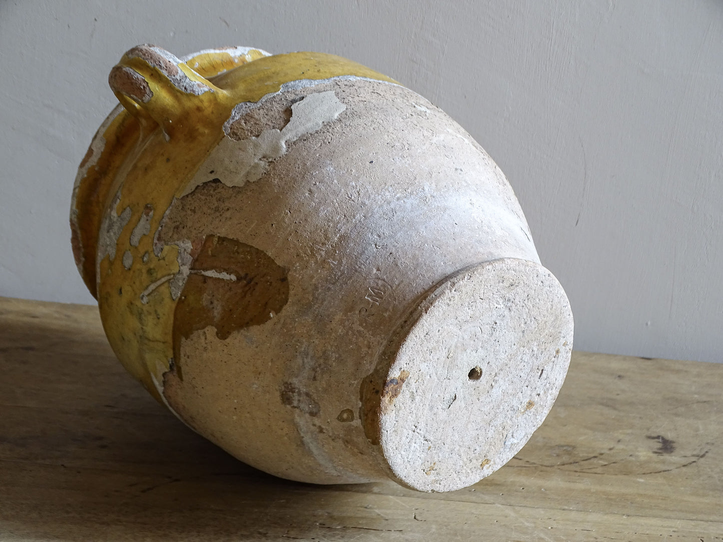 Antique French confit pot with weathered mustard-yellow glaze, twin handles and areas of exposed natural earthenware.