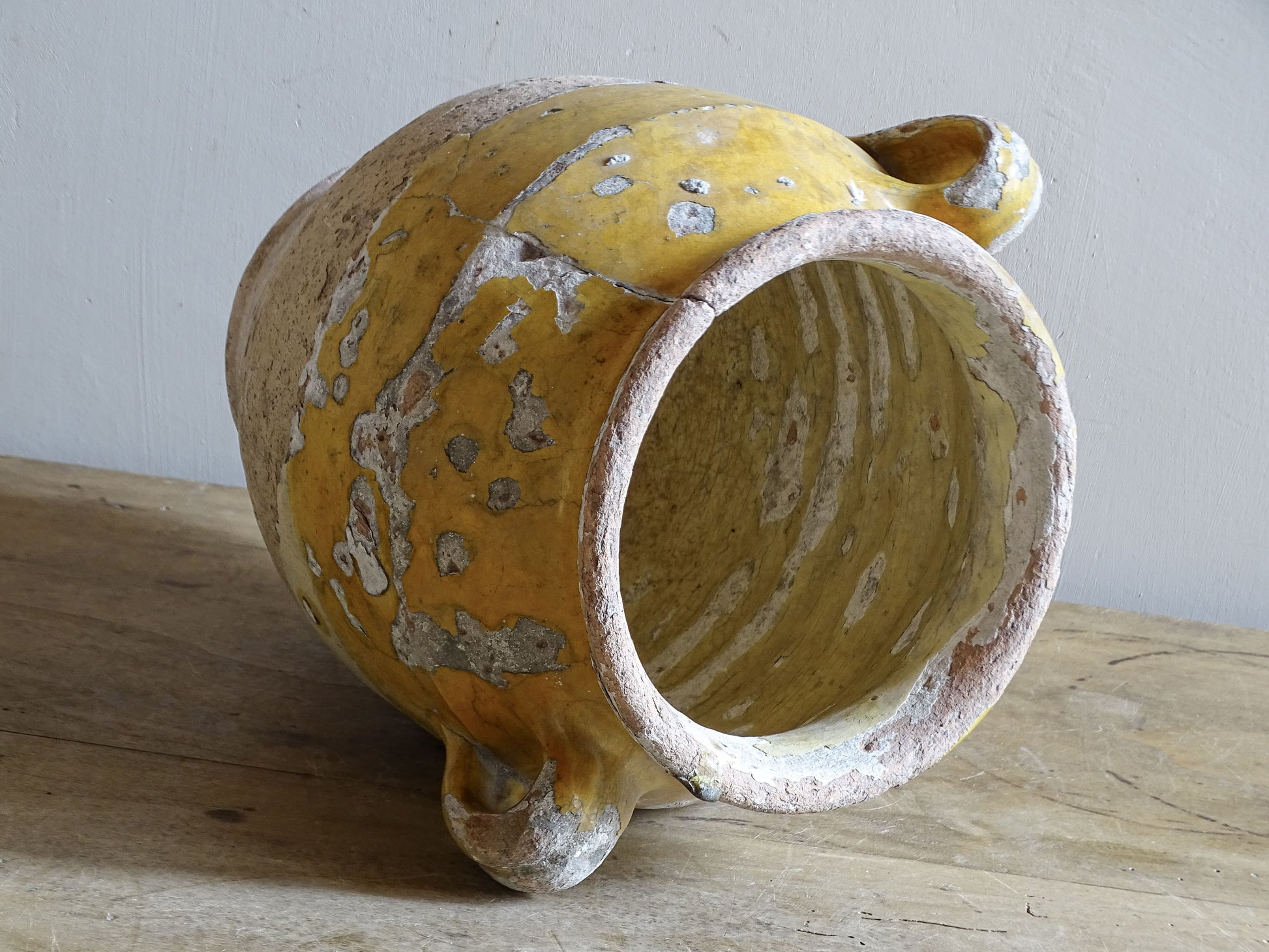 Antique French confit pot with weathered mustard-yellow glaze, twin handles and areas of exposed natural earthenware.