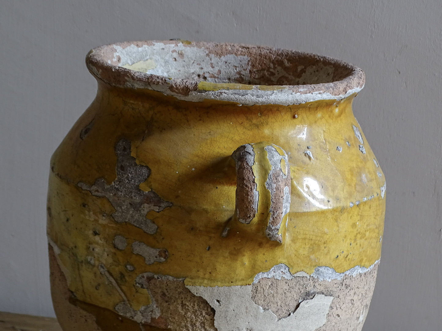 Antique French confit pot with weathered mustard-yellow glaze, twin handles and areas of exposed natural earthenware.