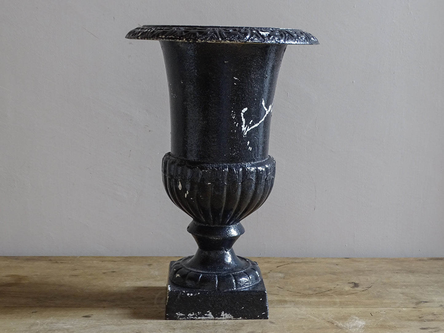 Antique French cast iron Médici urn planter with black painted finish, flared rim, gadrooned detail and square pedestal base.
