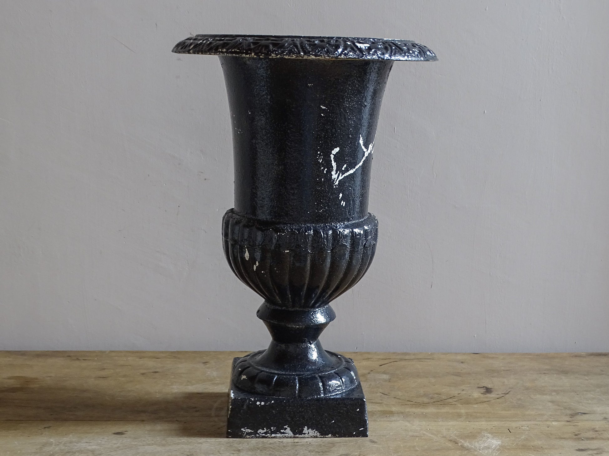 Antique French cast iron Médici urn planter with black painted finish, flared rim, gadrooned detail and square pedestal base.