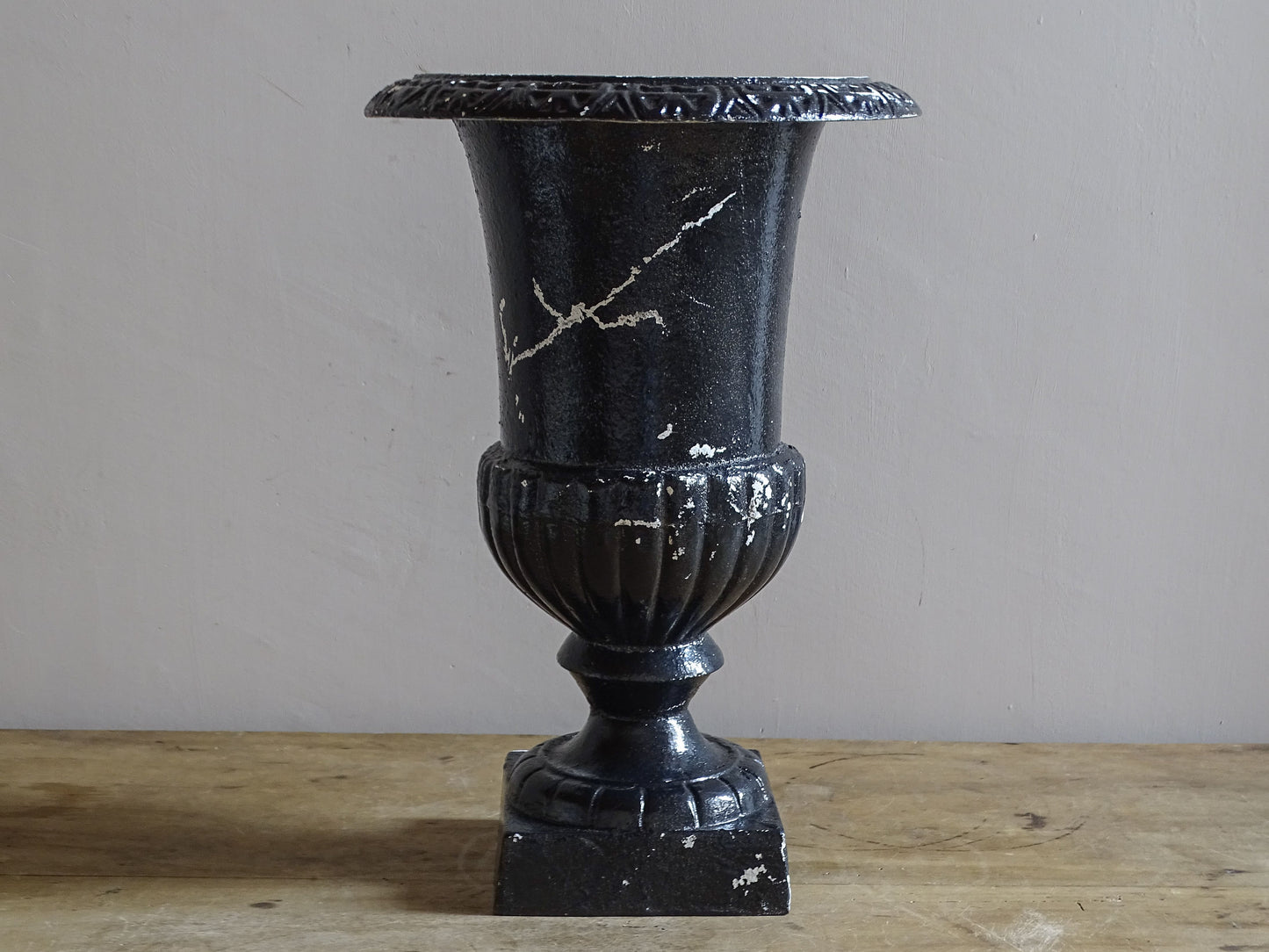 Antique French cast iron Médici urn planter with black painted finish, flared rim, gadrooned detail and square pedestal base.