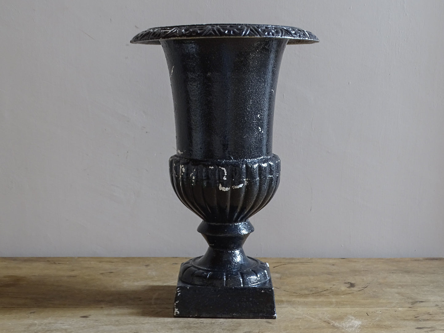 Antique French cast iron Médici urn planter with black painted finish, flared rim, gadrooned detail and square pedestal base.