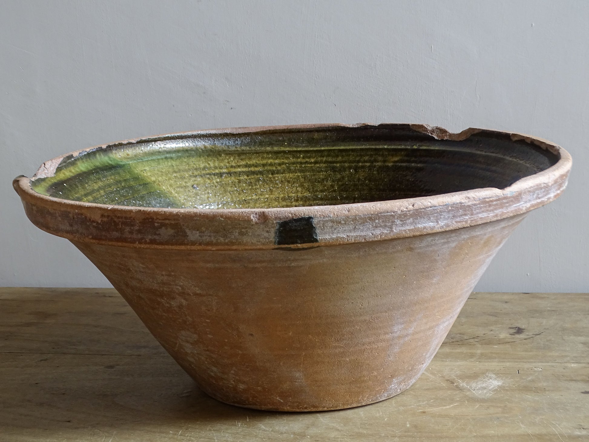 Large antique French tian bowl with dark olive-green glazed interior and unglazed terracotta exterior, early 20th century.