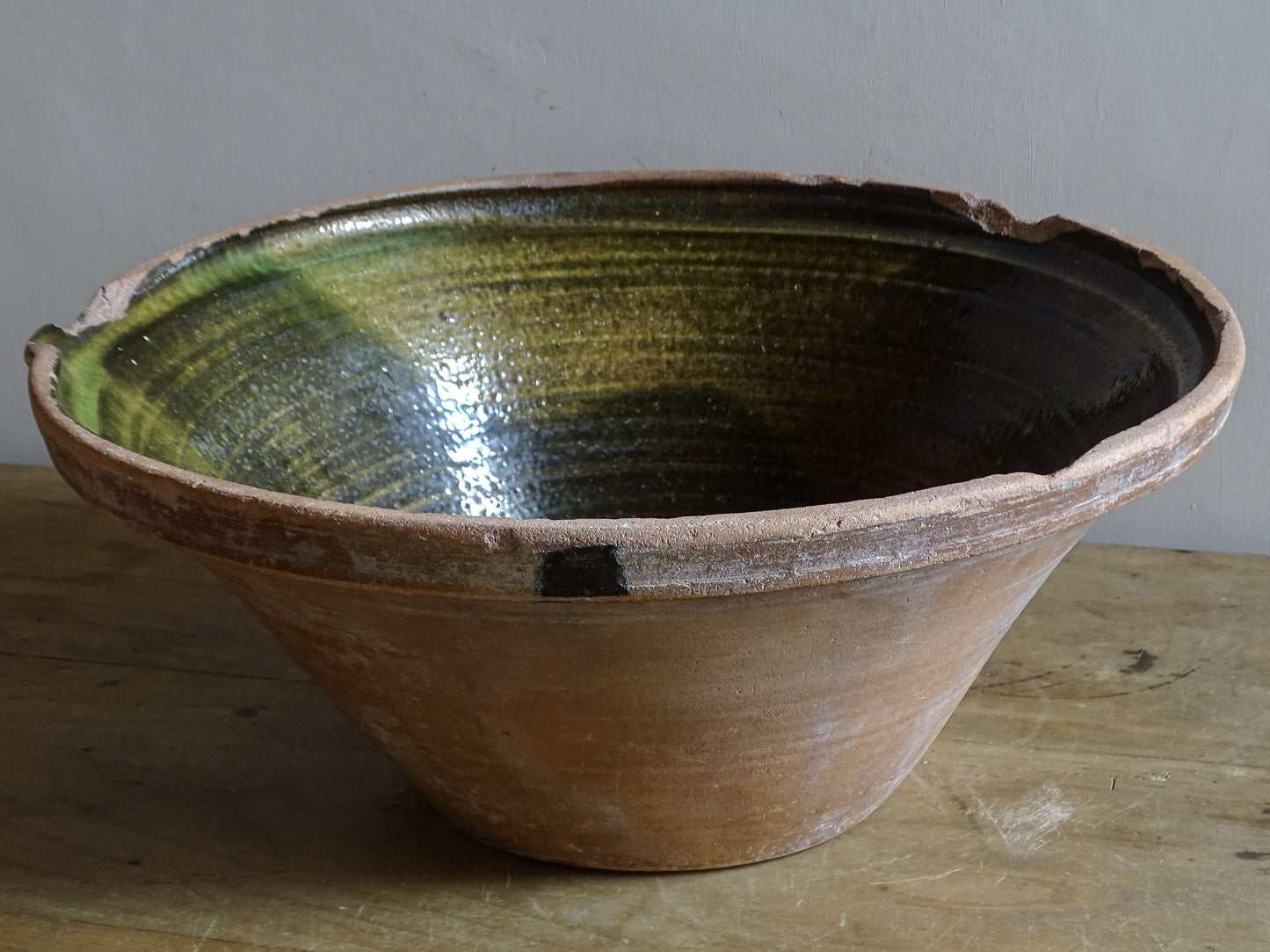 Large antique French tian bowl with dark olive-green glazed interior and unglazed terracotta exterior, early 20th century.