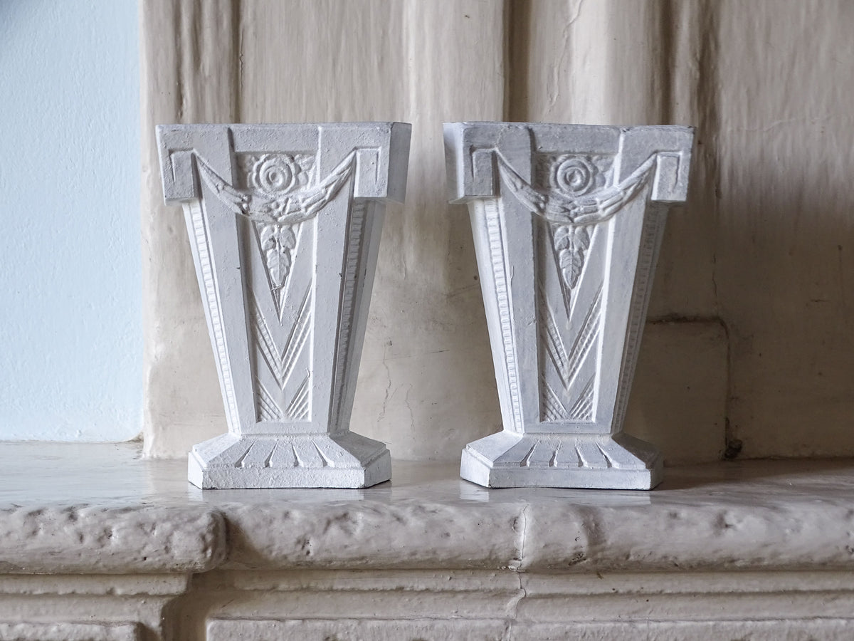 A decorative pair of French Art Deco cast aluminium vases in white, pictured on a country house fireplace