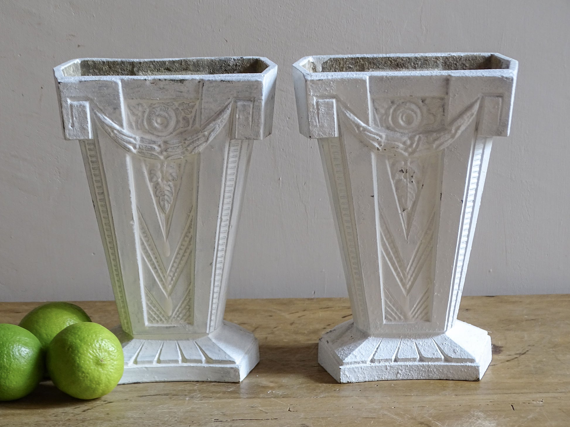 Pair of French Art Deco cast aluminium vases with white painted finish and geometric decoration.