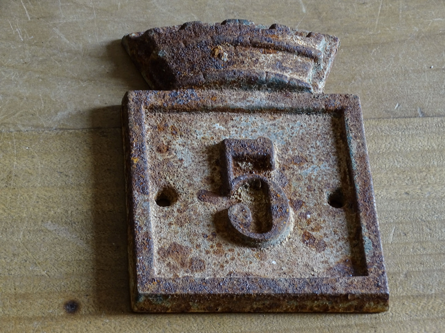Antique-style cast iron number 5 house plaque from Beaumont-du-Périgord, showing the raised numeral and distinctive architectural top.