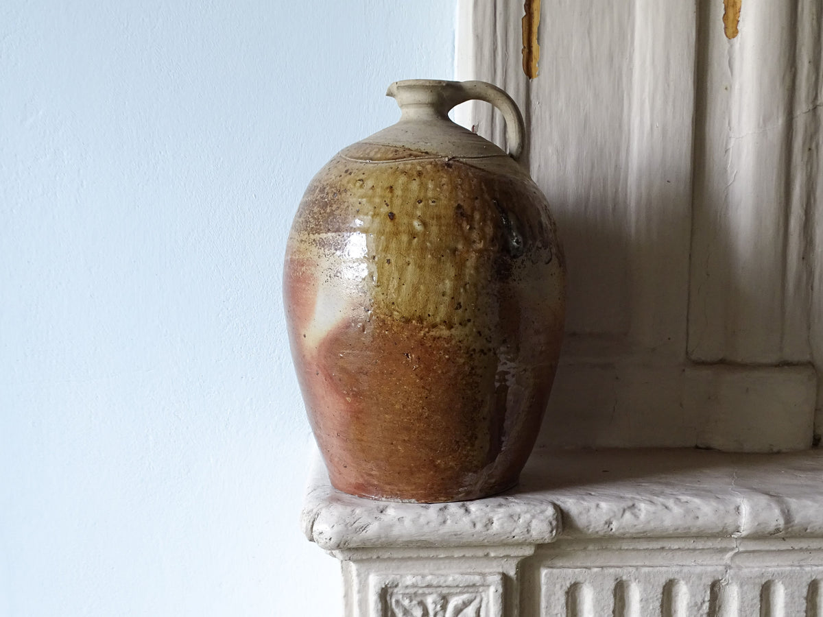 Large French antique stoneware pitcher with brown-red glaze, displayed on a country house fireplace
