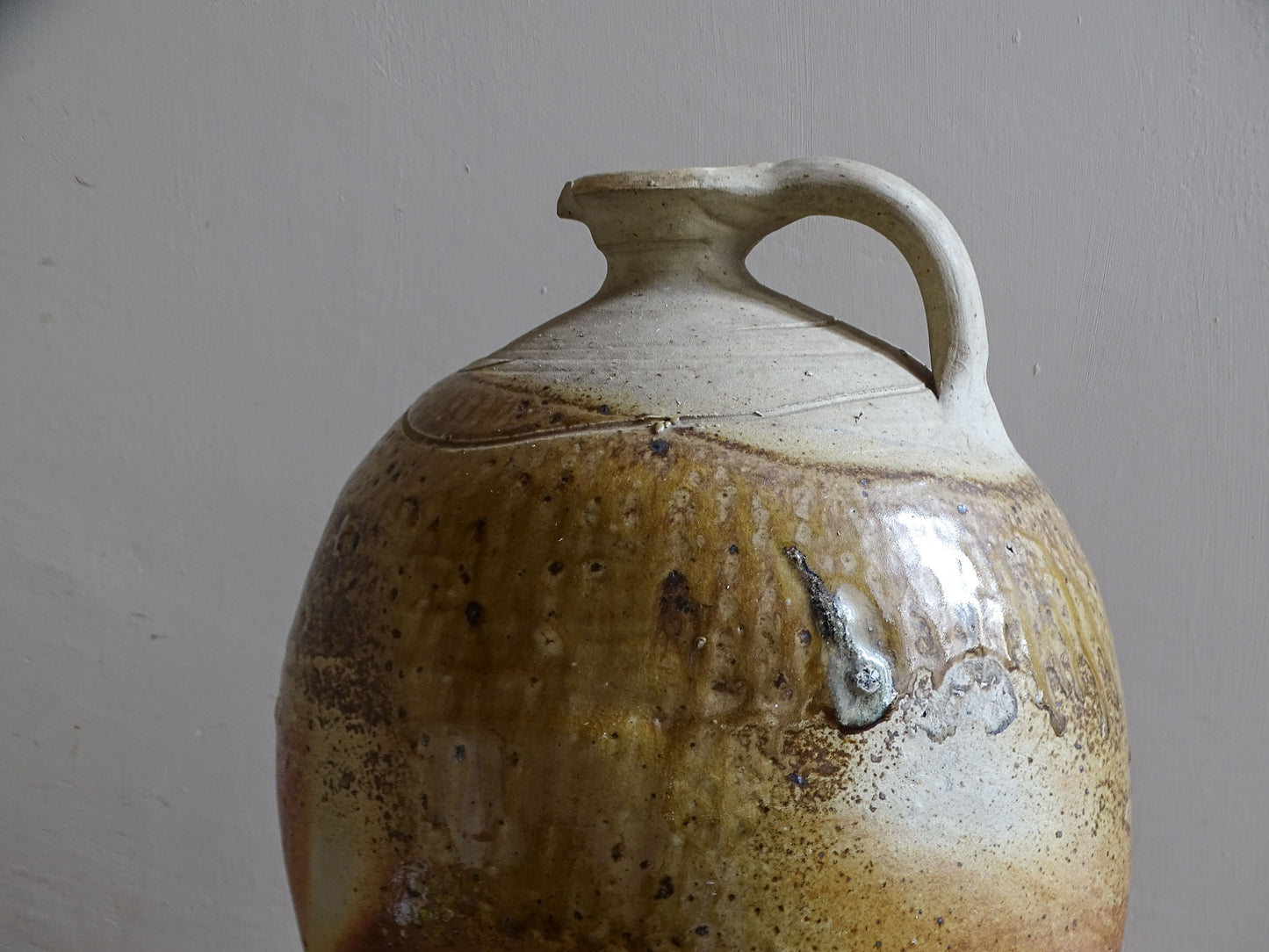 Rustic glazed stoneware cruche with tall ovoid body and handle