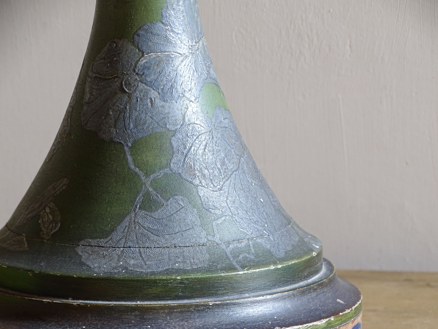 Close-up of raised silver flowers on green Art Nouveau painted wood lamp
