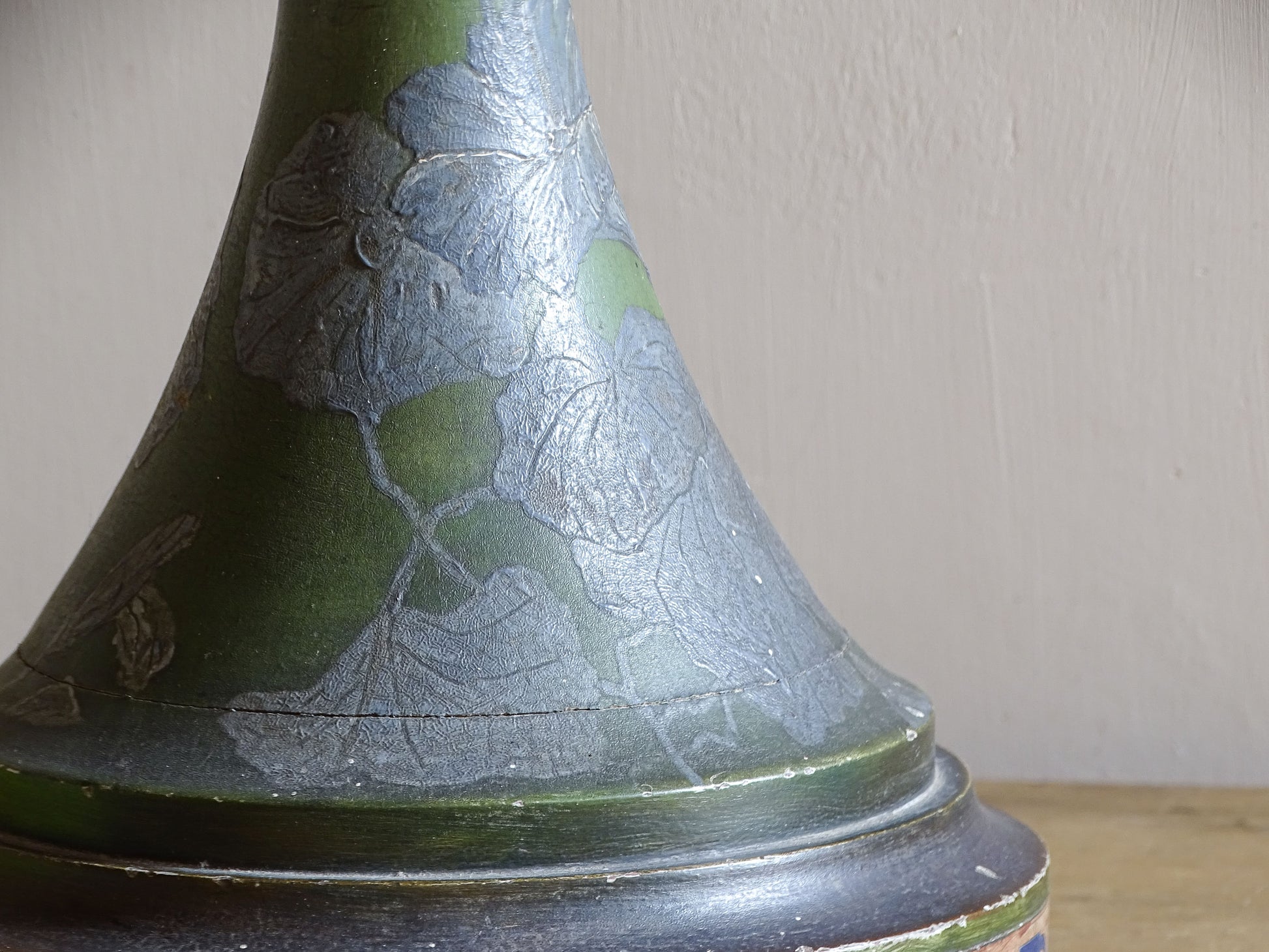 Close-up of raised silver flowers on green Art Nouveau painted wood lamp