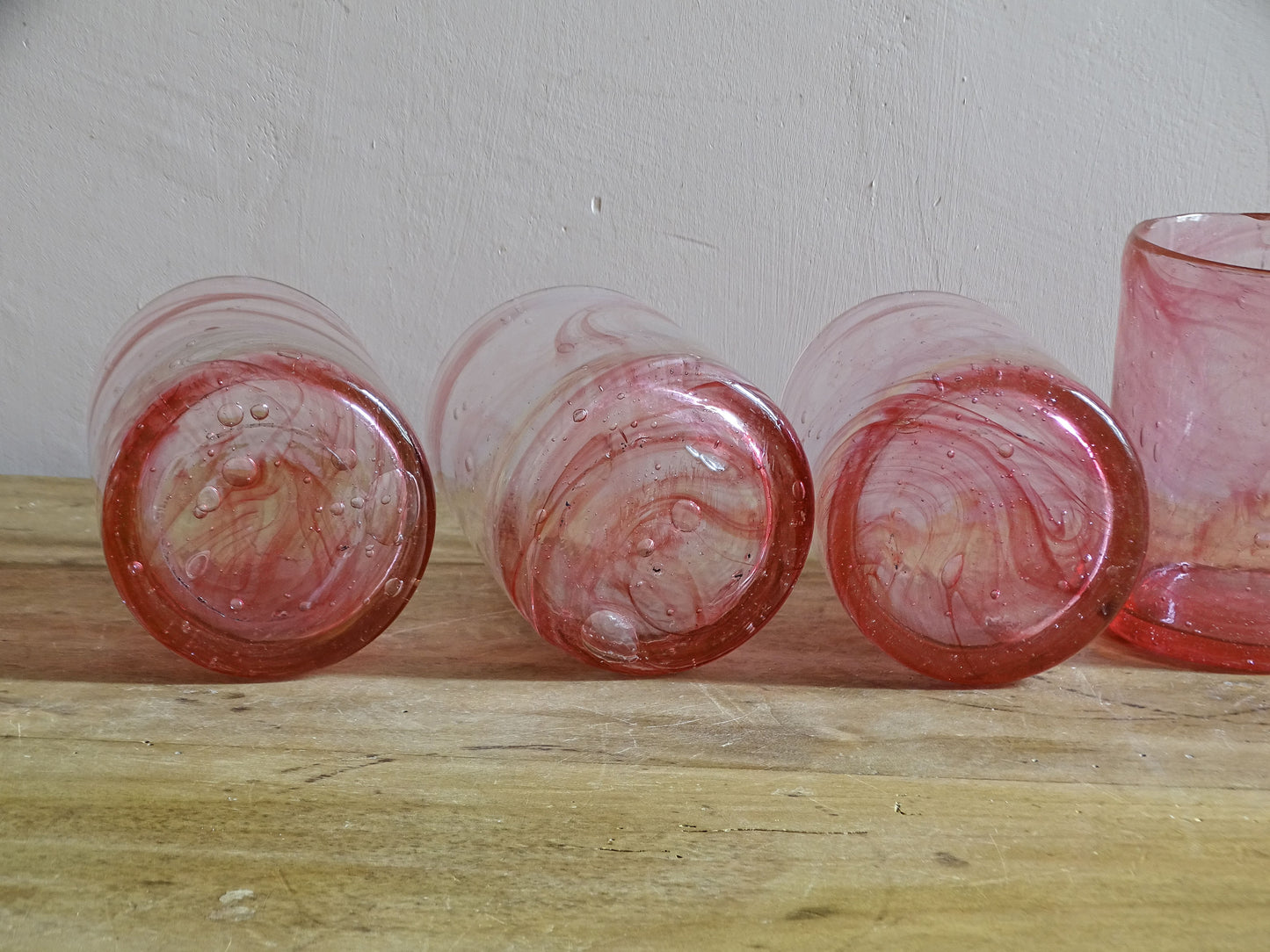 Hand-blown pink glass tumblers with bubbles and rose-coloured swirls