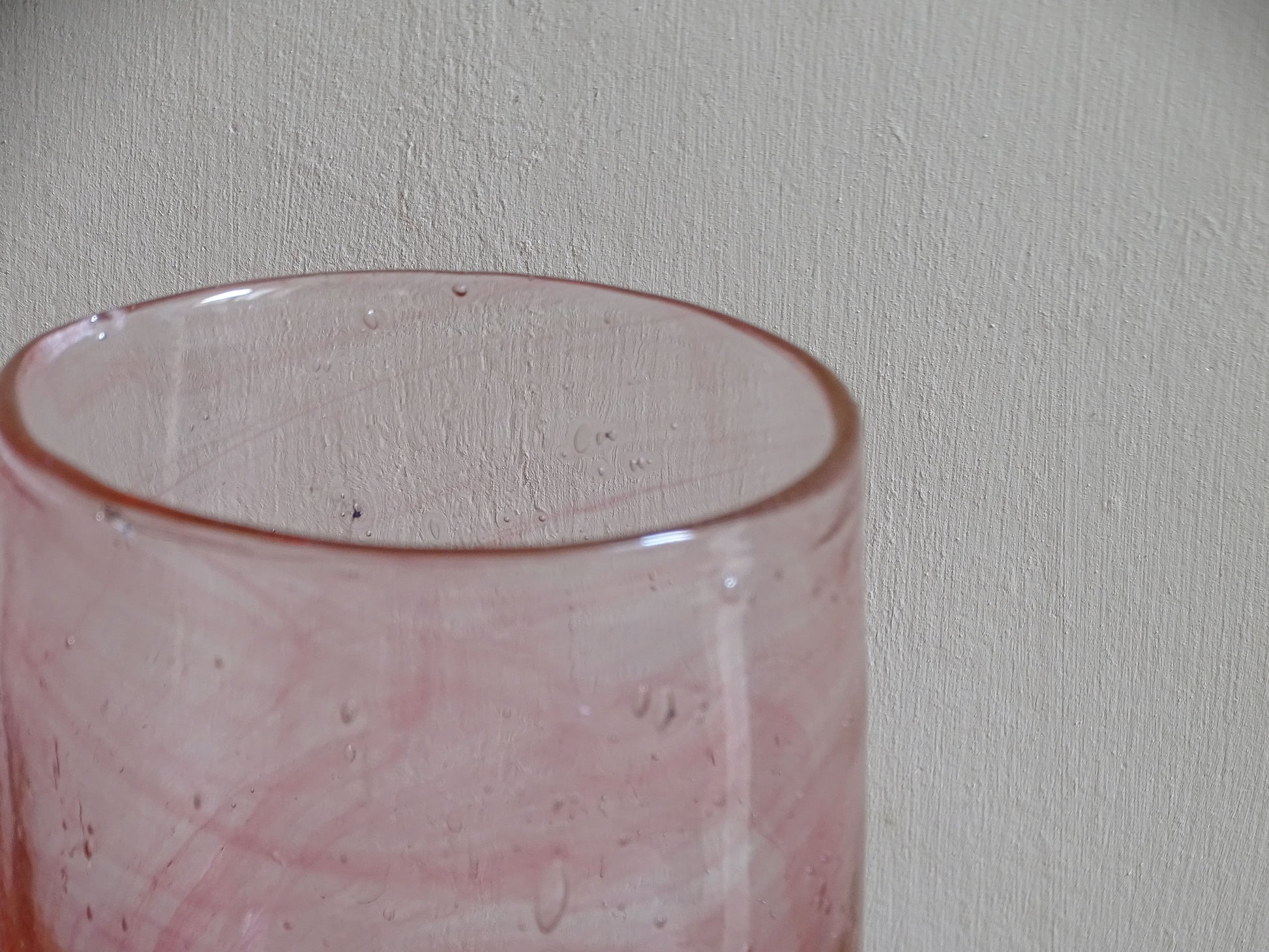 Pale pink hand-blown glass tumbler with deeper rose swirls and bubbles