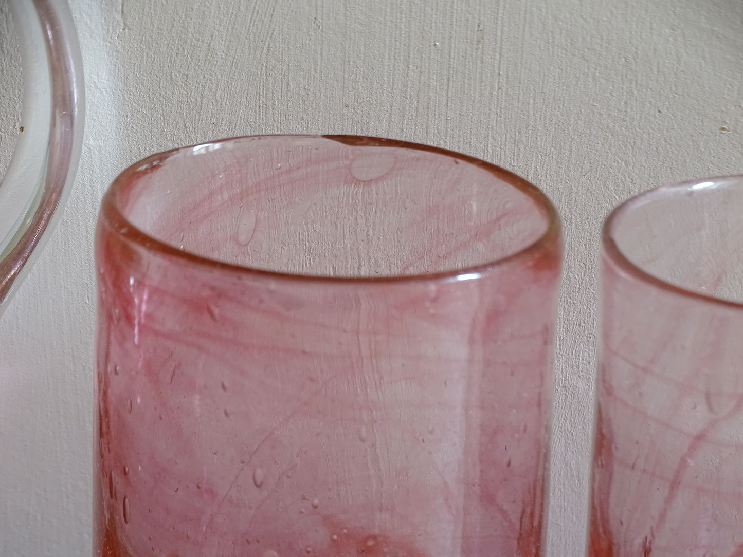 Vintage pink glass tumbler showing irregular handmade rim and colour variation