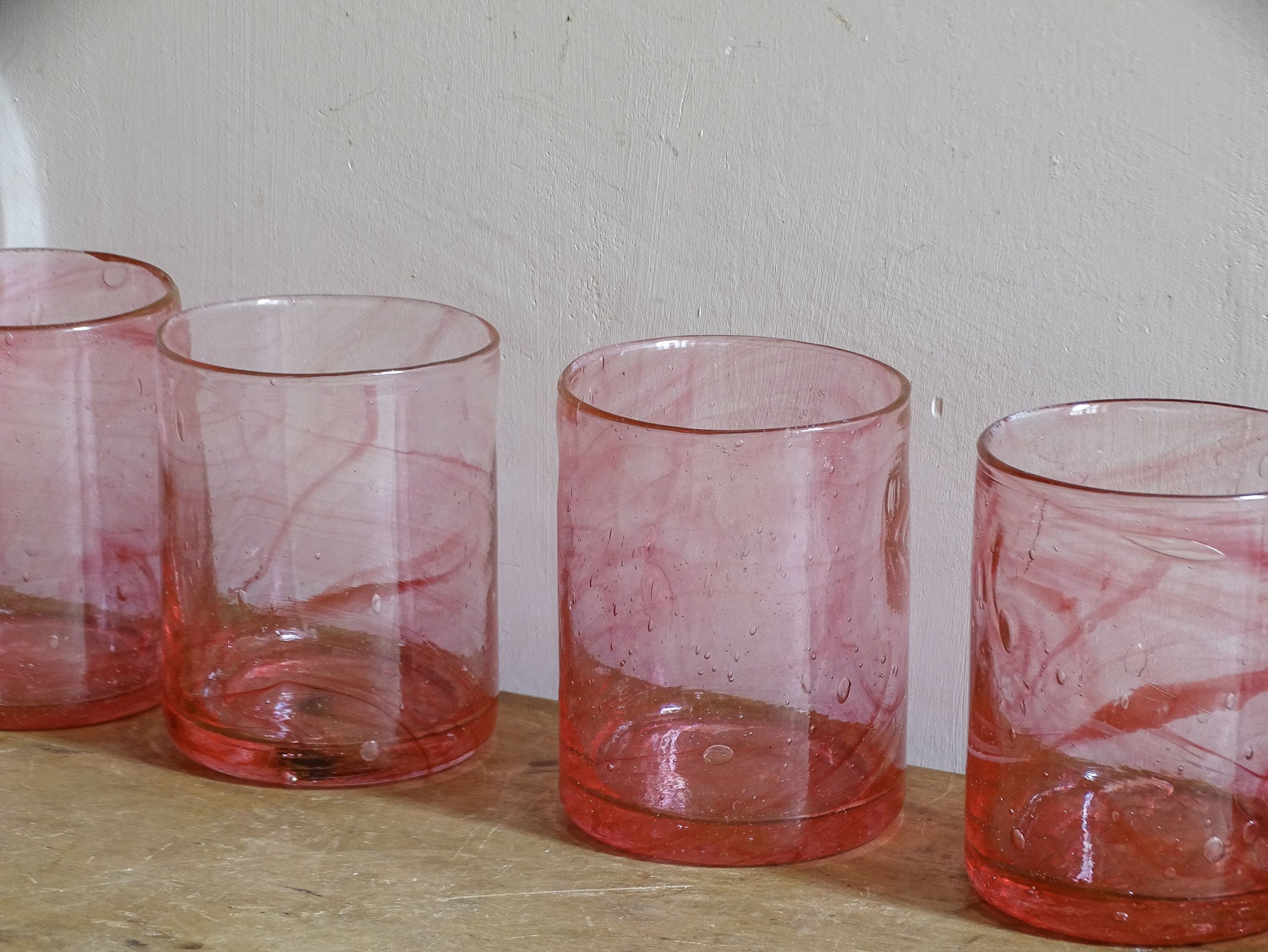 Vintage handmade pink glass tumblers with swirling colour and trapped bubbles