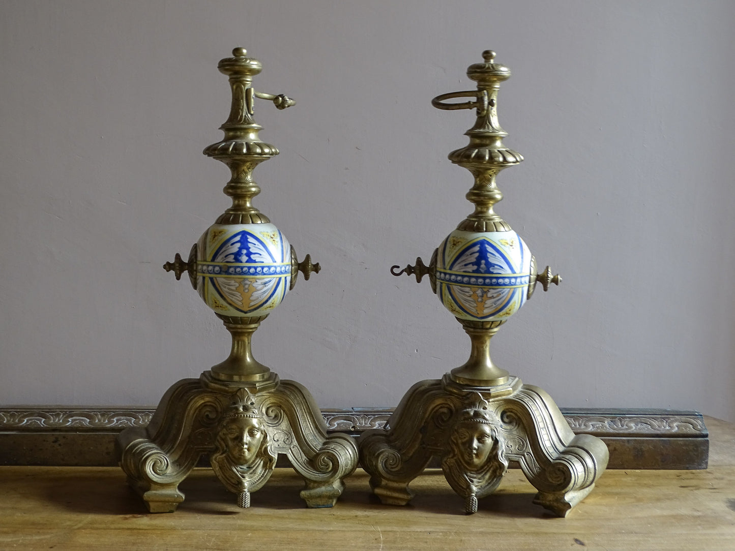 Large antique French andirons with hand-painted ceramic globes and aged brass patina