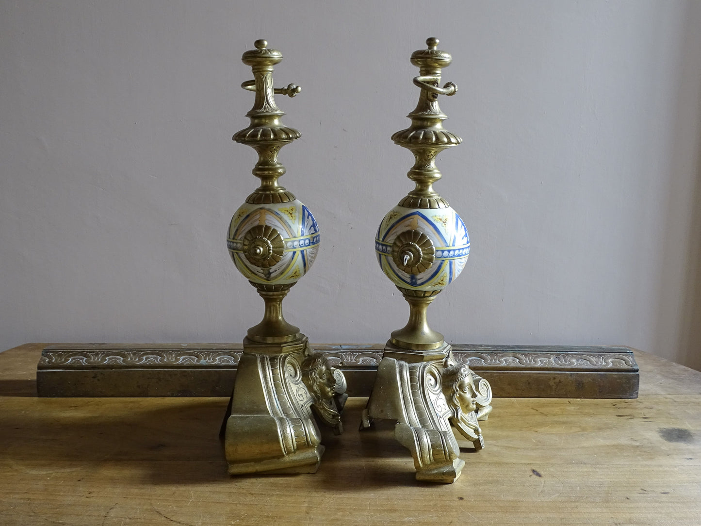 Antique French brass landiers with female mascaron bases and ceramic spheres