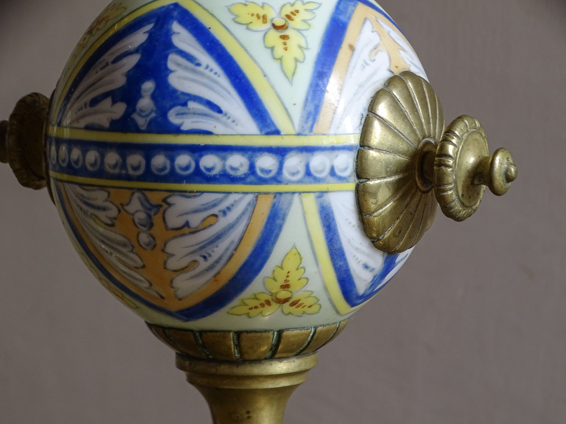 Hand-painted polychrome ceramic globe mounted within an antique French brass chenet