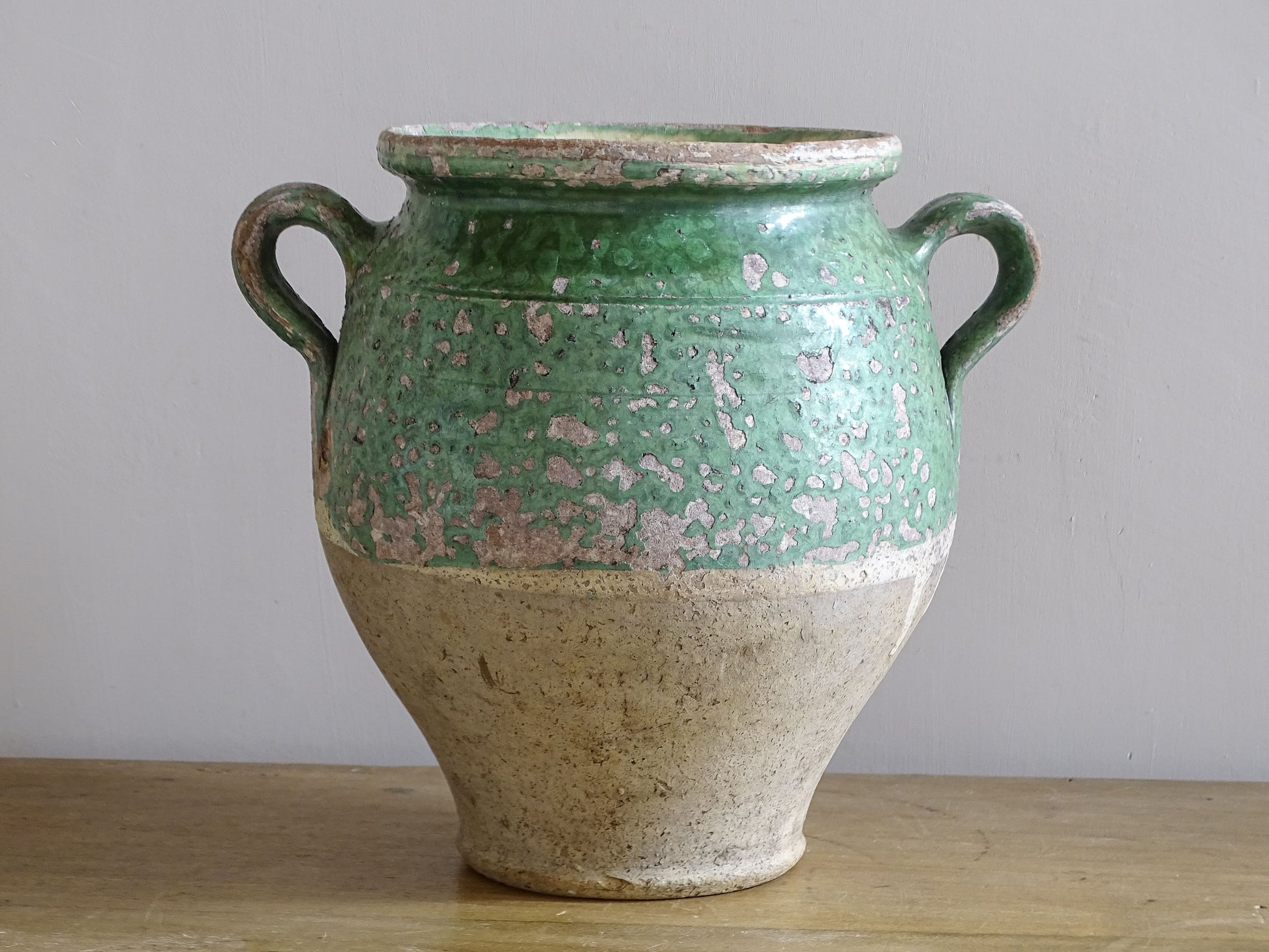 Two-handled French earthenware pot with timeworn green glaze