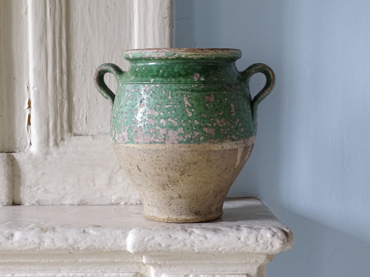 Antique French confit pot with green glaze displayed on a country house fireplace
