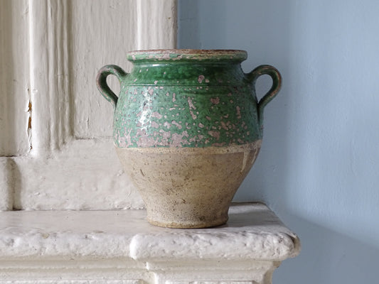 Antique French confit pot with green glaze displayed on a country house fireplace