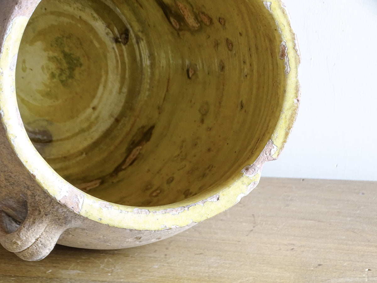Interior of antique French confit pot showing traditional yellow glaze and age-related wear