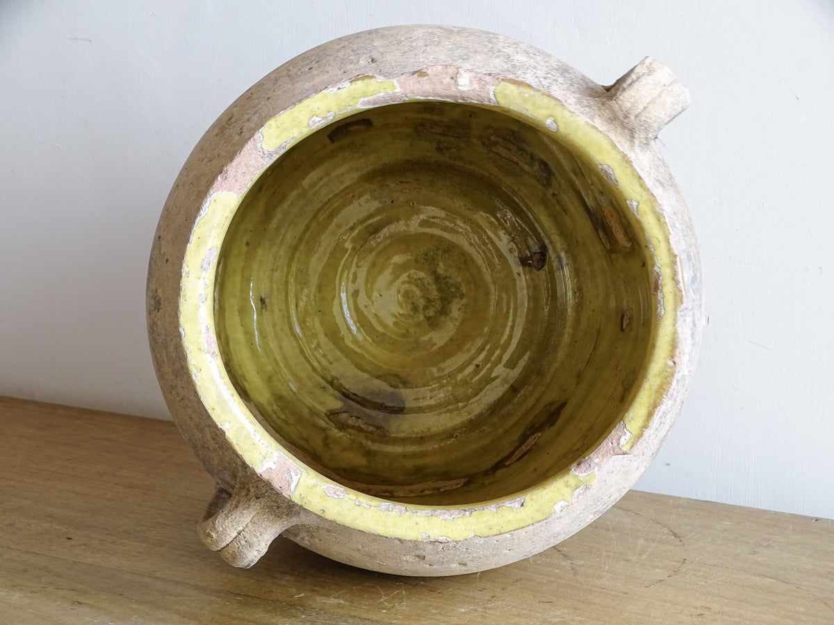 Interior of antique French confit pot showing traditional yellow glaze and age-related wear