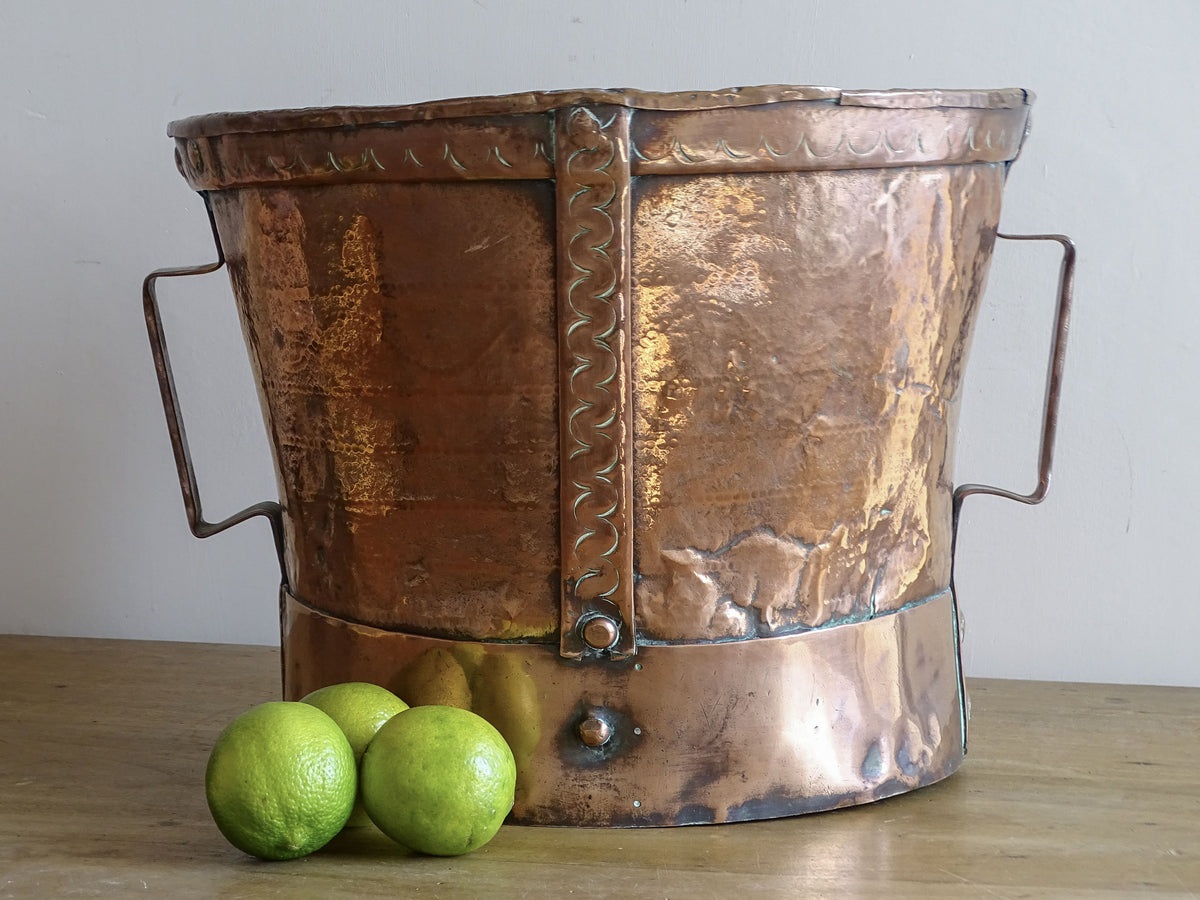 18th century French copper vessel displayed with fresh limes showing its substantial scale and aged patina