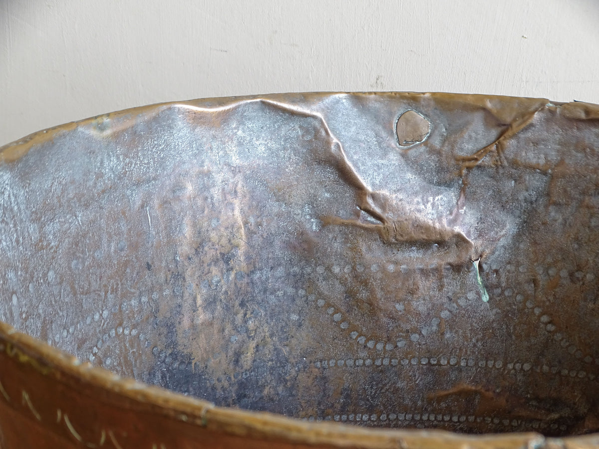 Interior detail of antique copper vessel showing old repairs, oxidation and extensive signs of historic use