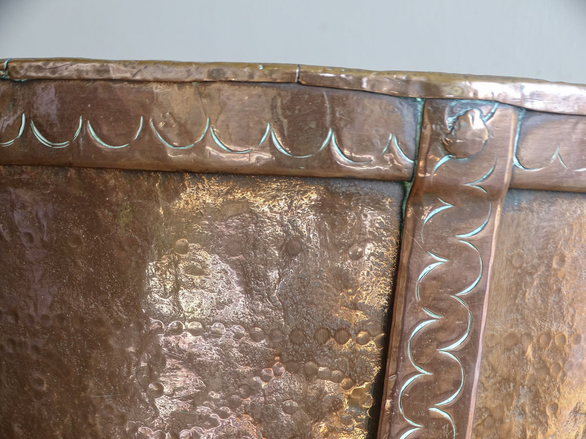 Close-up of punched curved decoration around the rim of an antique French copper vessel