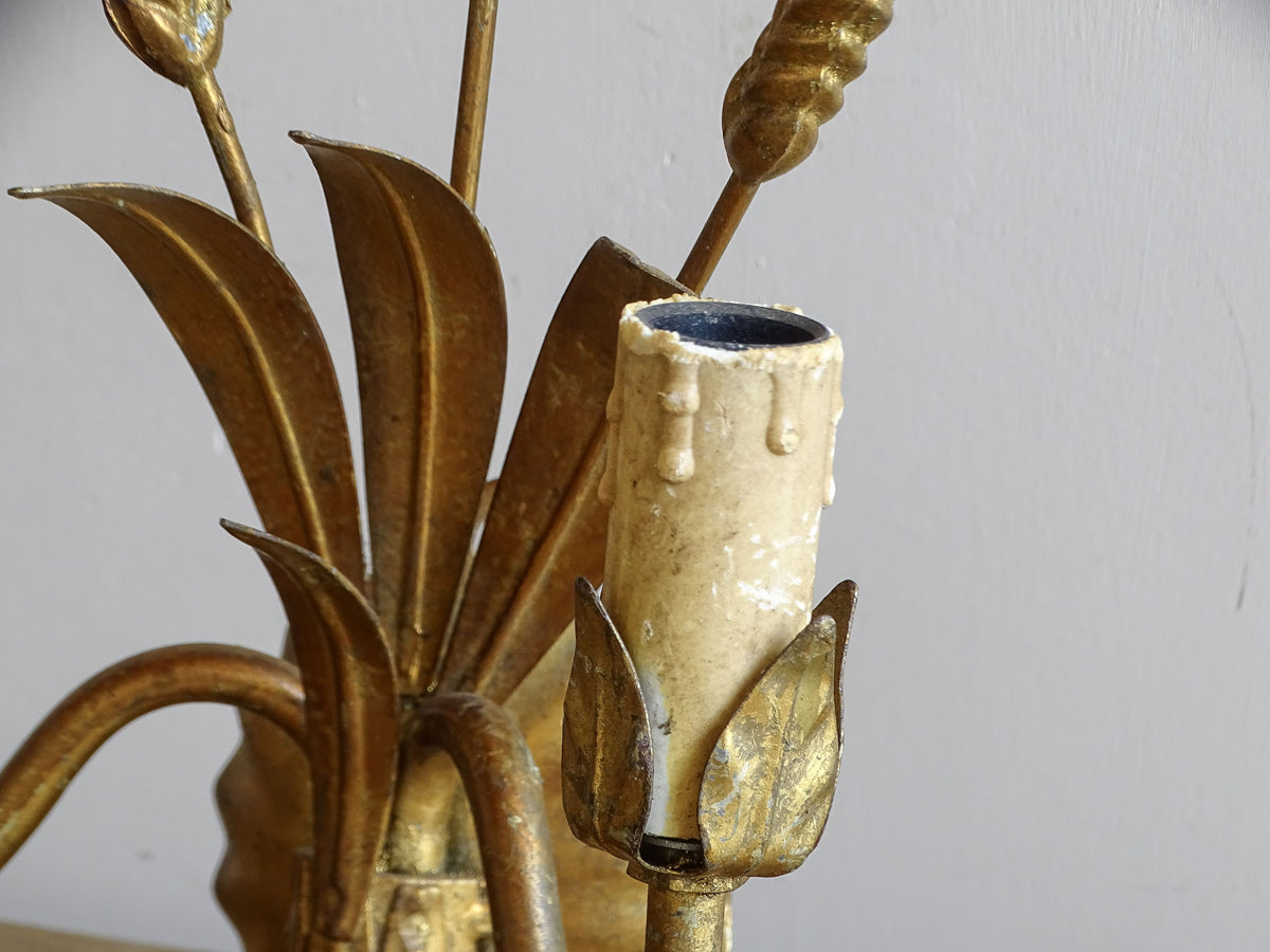Detail of leaf-shaped candle cup and aged faux-wax sleeve on gilt metal wall sconce